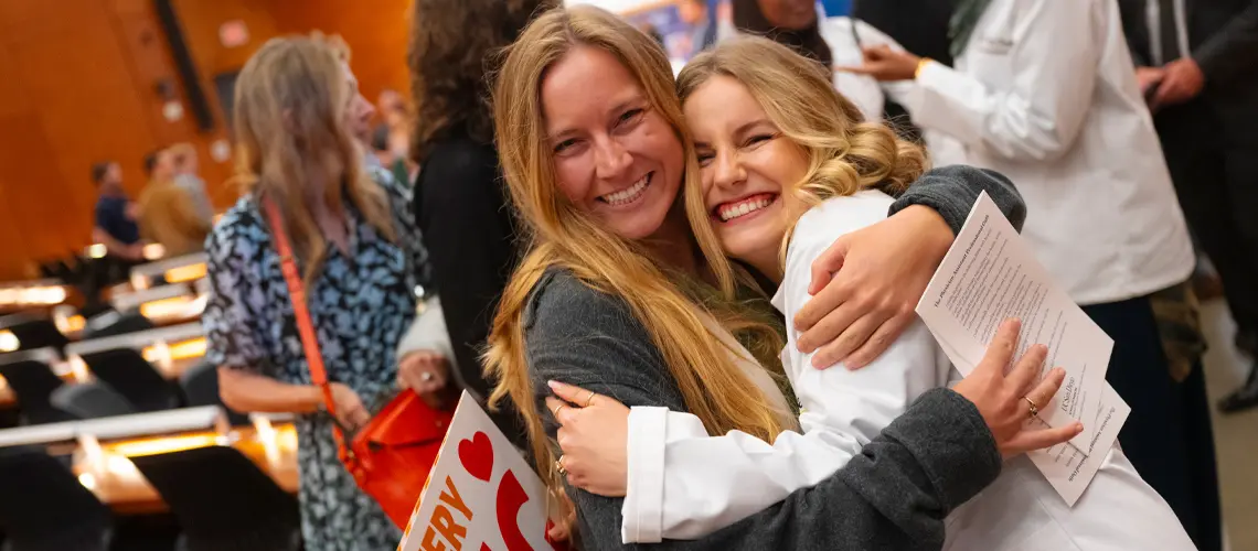 Two females hugging and smiling at the camera
